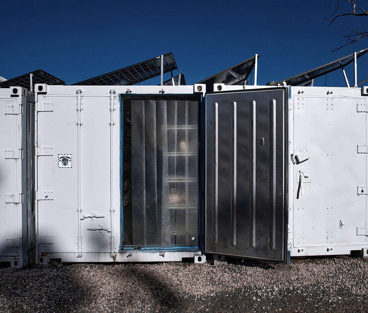 One of our grow rooms in Lawson: a shipping container with its door open, racks inside, solar panels on the roof